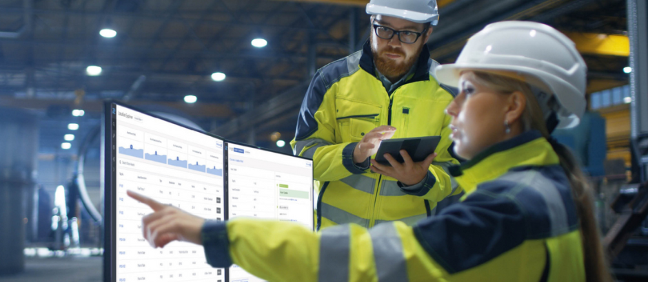 Man and woman in PPE looking at a computer monitor