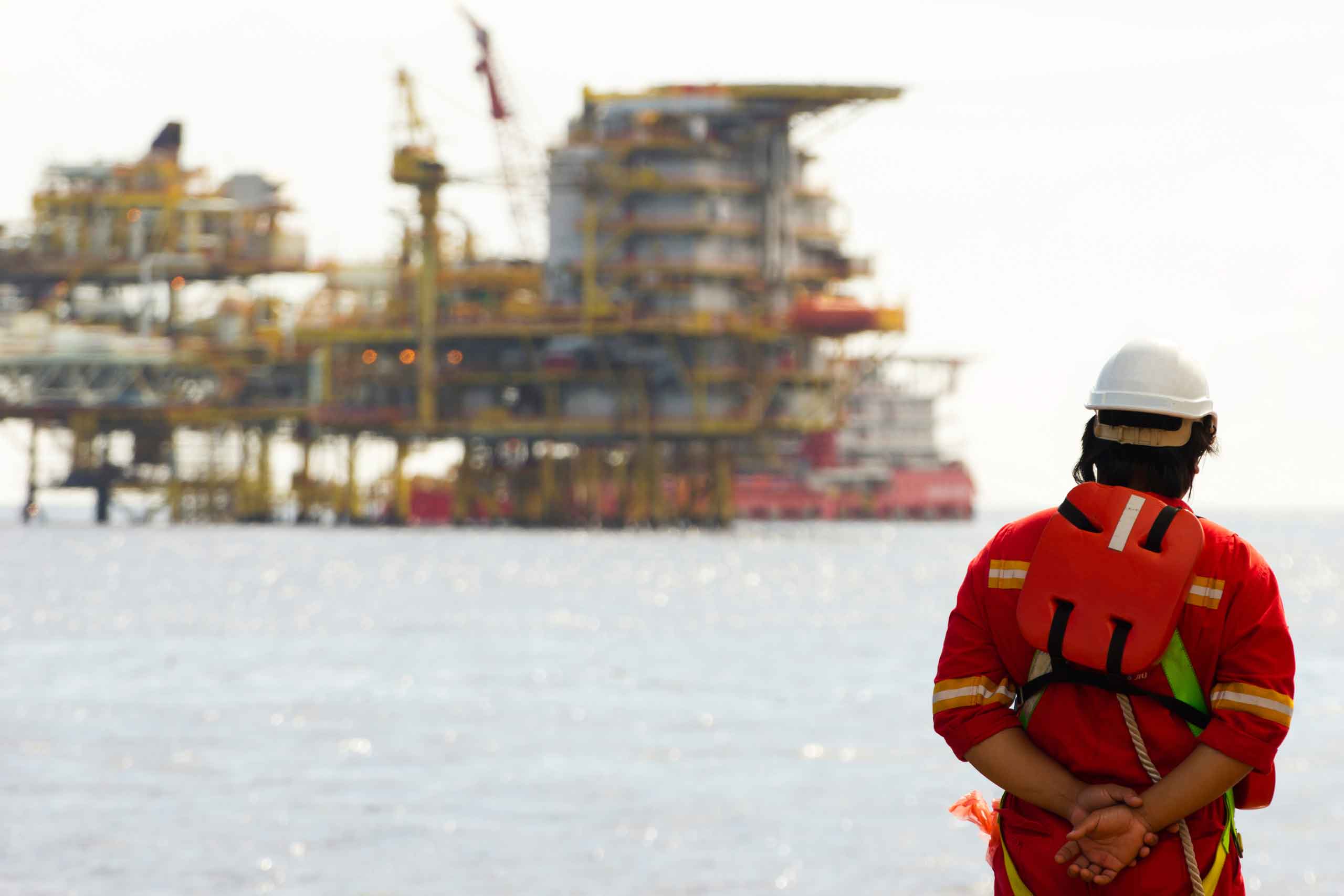 Marine surveyor looking across the sea to an oil rig and vessel